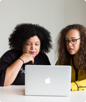 Two colleagues reviewing work together at a laptop