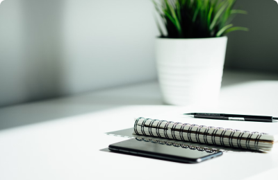 A quiet desk with a notebook, pen, and plant